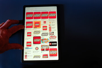 Naklejka premium Hand holding tablet, on LEGO icon on black background, February 21, 2025