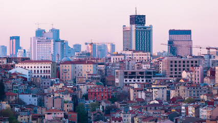 Istanbul skyline with mix of historic and modern architecture at dusk. Cityscape showcases traditional low-rise buildings in foreground, while contemporary skyscrapers in background