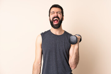 Fototapeta premium Caucasian sport man with beard making weightlifting over isolated background shouting to the front with mouth wide open