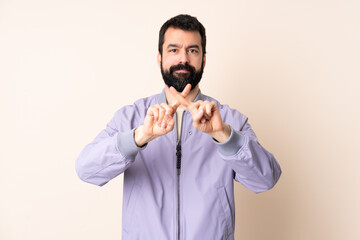 Caucasian man with beard wearing a jacket over isolated background making stop gesture with her hand to stop an act