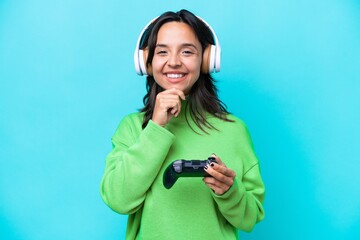 Young hispanic woman playing with a video game controller isolated on blue background happy and smiling © luismolinero