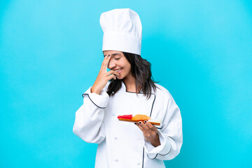 Young hispanic chef woman holding sashimi isolated on blue background laughing