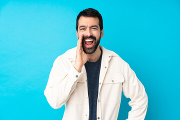 Young handsome man with white corduroy jacket over isolated blue background shouting with mouth wide open