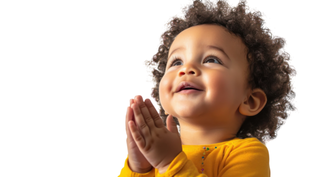 Child with curly hair joyfully clasping hands and smiling in bright yellow shirt against white background