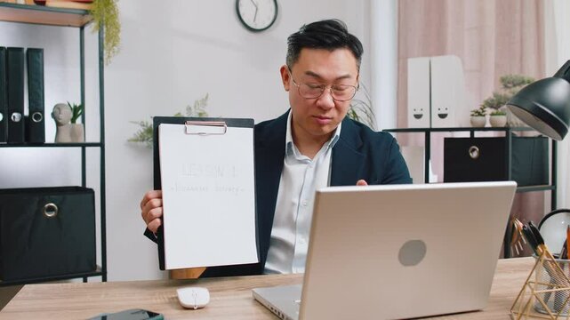 Asian businessman freelancer making online presentation video laptop call education lessons for remote study student classes at office workplace. Male Chinese in suit demonstrates graphic analytics