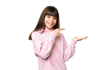 Little girl over isolated green chroma key background holding copyspace imaginary on the palm to...