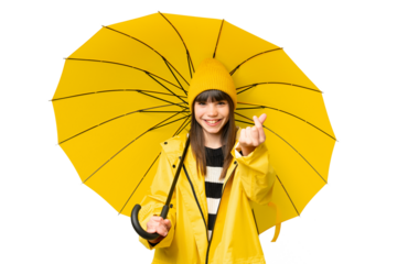 Little girl with rainproof coat and umbrella over isolated chroma key background making money gesture