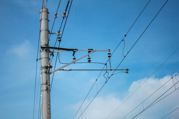 concrete electric pole with cables stretching across the blue sky