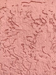 Textured pink stucco wall, rough plaster surface