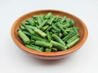 Long beans (Vigna Unguiculata ssp. Sesquipedalis) that have been cut into pieces in a wooden bowl on a white background. High angle view. 