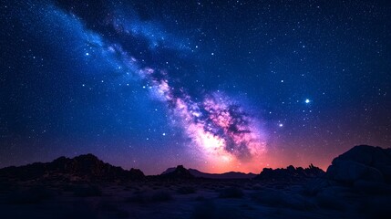 The Milky Way core illuminates a halo indigo starry sky, captured in time-lapse with long exposure over rocky desert terrain using an ultra-wide-angle lens.  