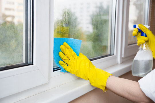 Cleaning A Window With A Spray Bottle And Sponge Cloth