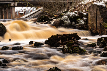 winter landscape with rapid river flow, blurred water surface, blurred movement, rapid stream of wild river