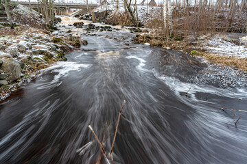 winter landscape with rapid river flow, blurred water surface, blurred movement, rapid stream of wild river