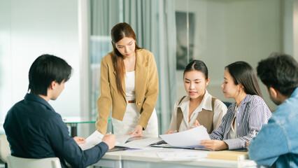 A professional meeting with a diverse group discussing documents, showcasing collaboration and engagement in a modern workspace. © Leny Studio
