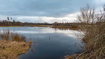 latvian winter landscape with flooded lake, thin and light ice in places, reflections