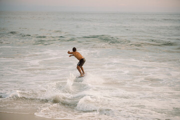 Surfer riding wave at sunset on skimboard