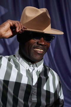 Smiling Man Wearing Hat with Checker Shirt Adjusting Hat
