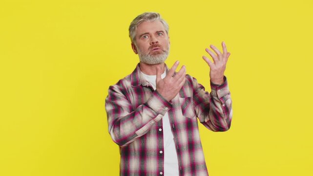 Mature man stretches arms wide, trying to snatch unseen object with determined excitement wonder. Guy on yellow background emphasizing intense focus on an elusive goal catches discounts and promotions