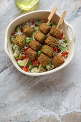 Serving tray with falafel skewers, couscous and vegetables, vertical shot on a grey granite background with space, high angle view