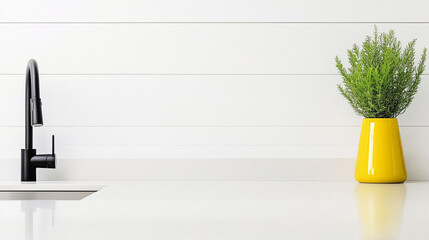 Modern kitchen sink with a yellow vase and green plant on a white countertop.