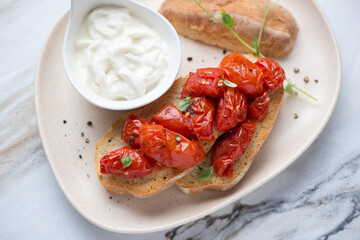Beige plate with stracciatella or stretched curd cheese and tomato bruschettas, horizontal shot, middle closeup, elevated view