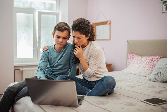 Mother and son exploring educational content on a laptop in boy's room - Powered by Adobe