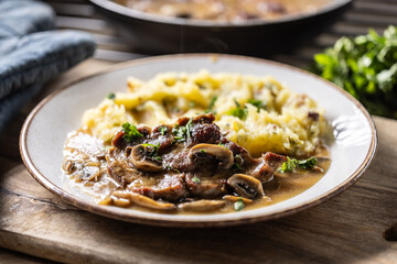 Roasted Pork Neck with mashed potatoes and mushroom sauce on a plate