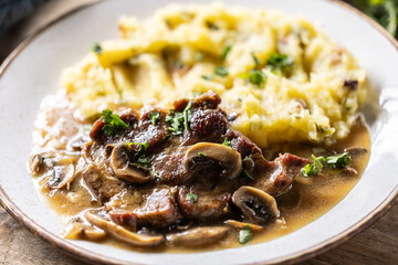 Roasted Pork Neck with mashed potatoes and mushroom sauce on a plate
