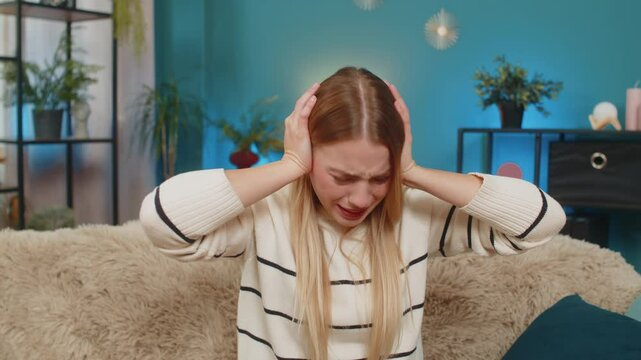Caucasian woman girl home sofa stressed by noisy neighbors drilling hammering loud music yelling. Trying relief covering ears annoyed hoping quiet calm peaceful indoor comfort tension ease soothing