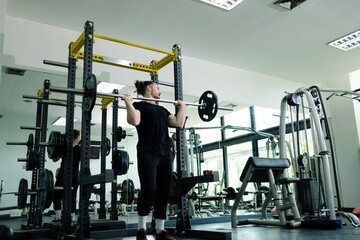 Fototapeta premium Young man using weight lifting exercise in fitness gym. Fitness concept.
