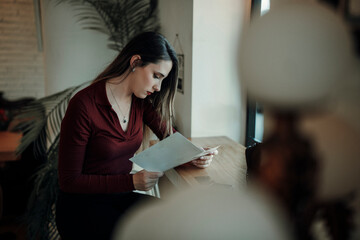 Chica joven con pelo largo tomando café y tortitas en cafetería estilo cozy