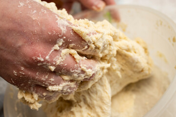 Woman hands mixing dough in a plastic bowl, soft focus close up