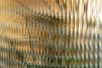 Exotic palm leaves shadows on golden background, plant silhouettes thru corrugated glass  texture, abstract backdrop for product placement