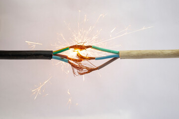 Sparks explosion between electrical cables, on white background, fire hazard concept, soft focus...