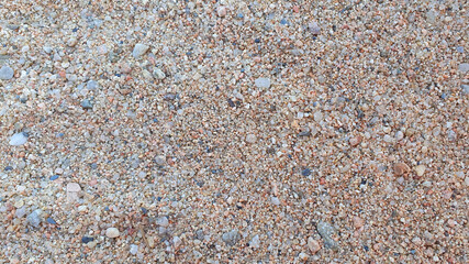 Little stones and sand in the summer day. Yellow sand on the beach near a sea.