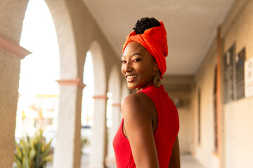 Smiling garifuna woman wearing traditional orange turban in archway