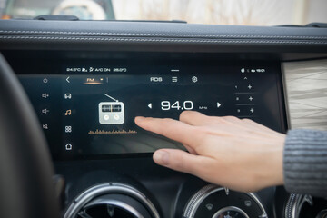 A detailed closeup view of a cars touchscreen dashboard displaying radio tuning and an engaging...