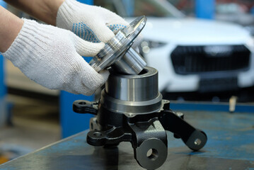 Car suspension repair. An auto mechanic prepares the front wheel hub for replacement and the installation of a new front hub bearing.The right rotary lever. Inspection and control of spare parts.