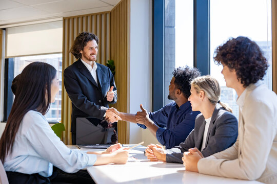 Team of diversity business people having agreement and handshake deal over new strategic strategy project on investment real estate with recognition and applause from other colleagues for partnership