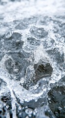 Obraz premium Close up view of white water foam and dark gray rocks, with a textured surface and dynamic motion. The image has a cool color palette and shows water