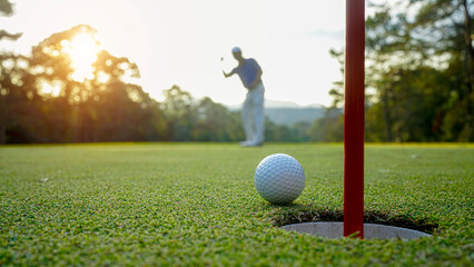 Golfer action to win after long putting golf ball in to the hole.