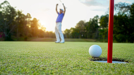 Golfer action to win after long putting golf ball in to the hole.