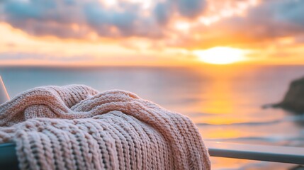 A knitted blanket on a balcony overlooking a serene ocean at dawn