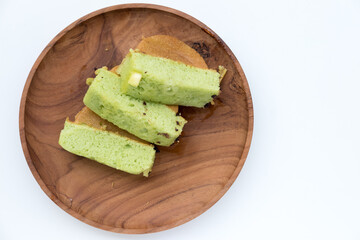Pukis slices on a wooden plate. Soft, light green cake with a honeycomb texture.
