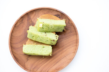 Pukis slices on a wooden plate. Soft, light green cake with a honeycomb texture.