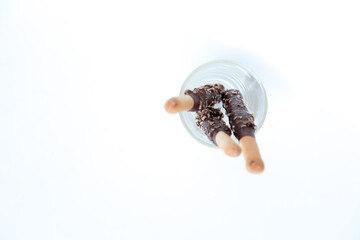 Blurred, top-down view of chocolate-covered bread sticks in a glass. Soft lighting and white space create a minimalist, artistic feel