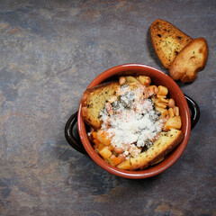 Zuppa di verdure con fagioli e pasta, spolverata con parmigiano grattugiato, ciotola con zuppa e pane tostato, spazio per testo