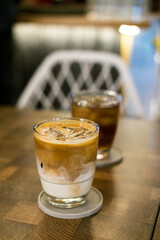 Hot latte & iced tea on cafe table. Layered coffee, cool iced beverage, indoor setting, warm drink, refreshment.