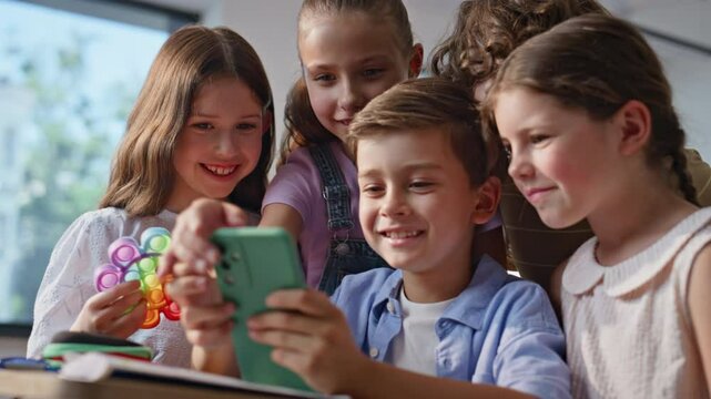 Smiling children playing cellphone sharing joyful moment at school break closeup